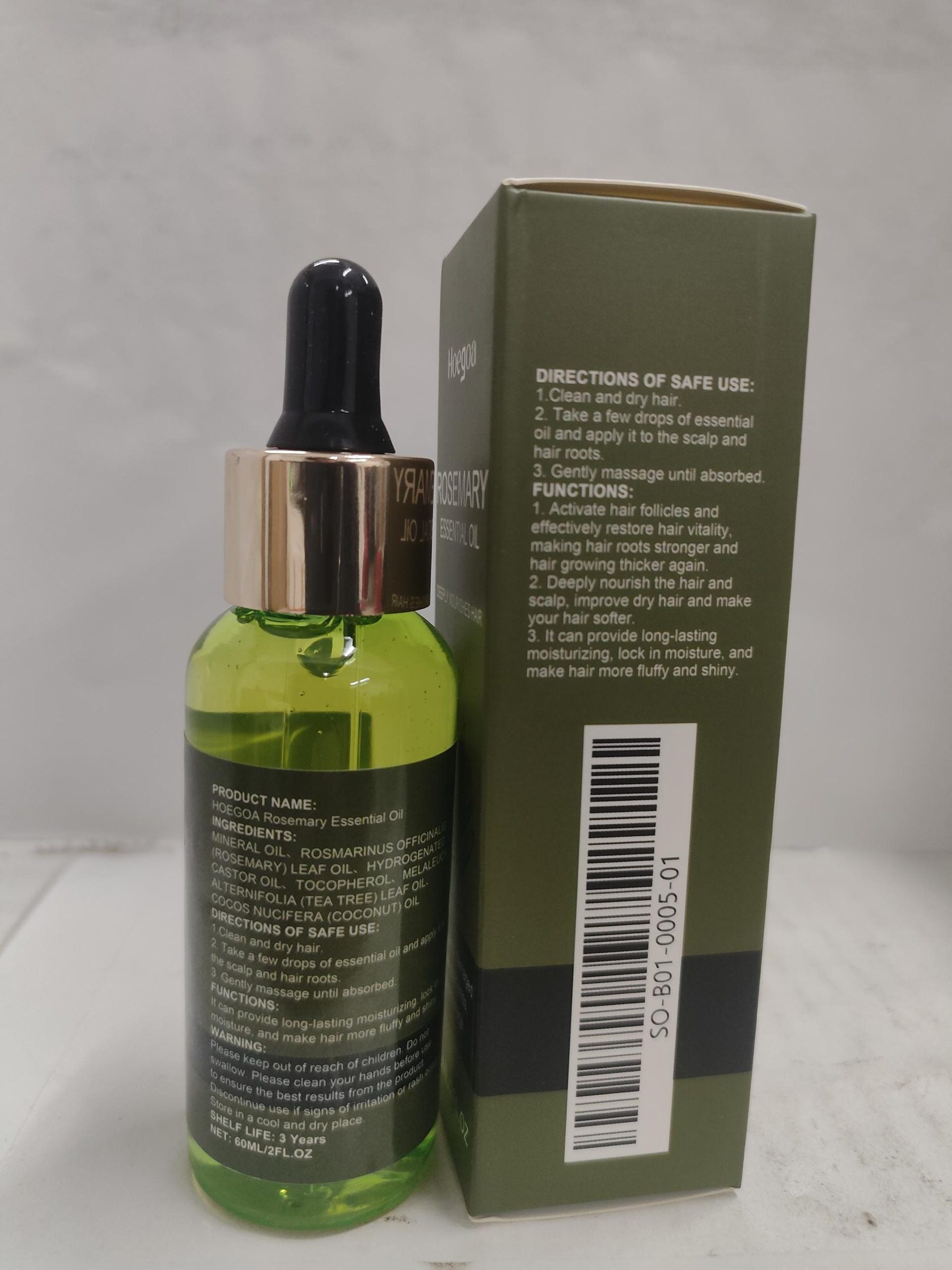 A bottle of hair growth essential oil with a dropper cap next to its green cardboard packaging box, set against a neutral gray background.