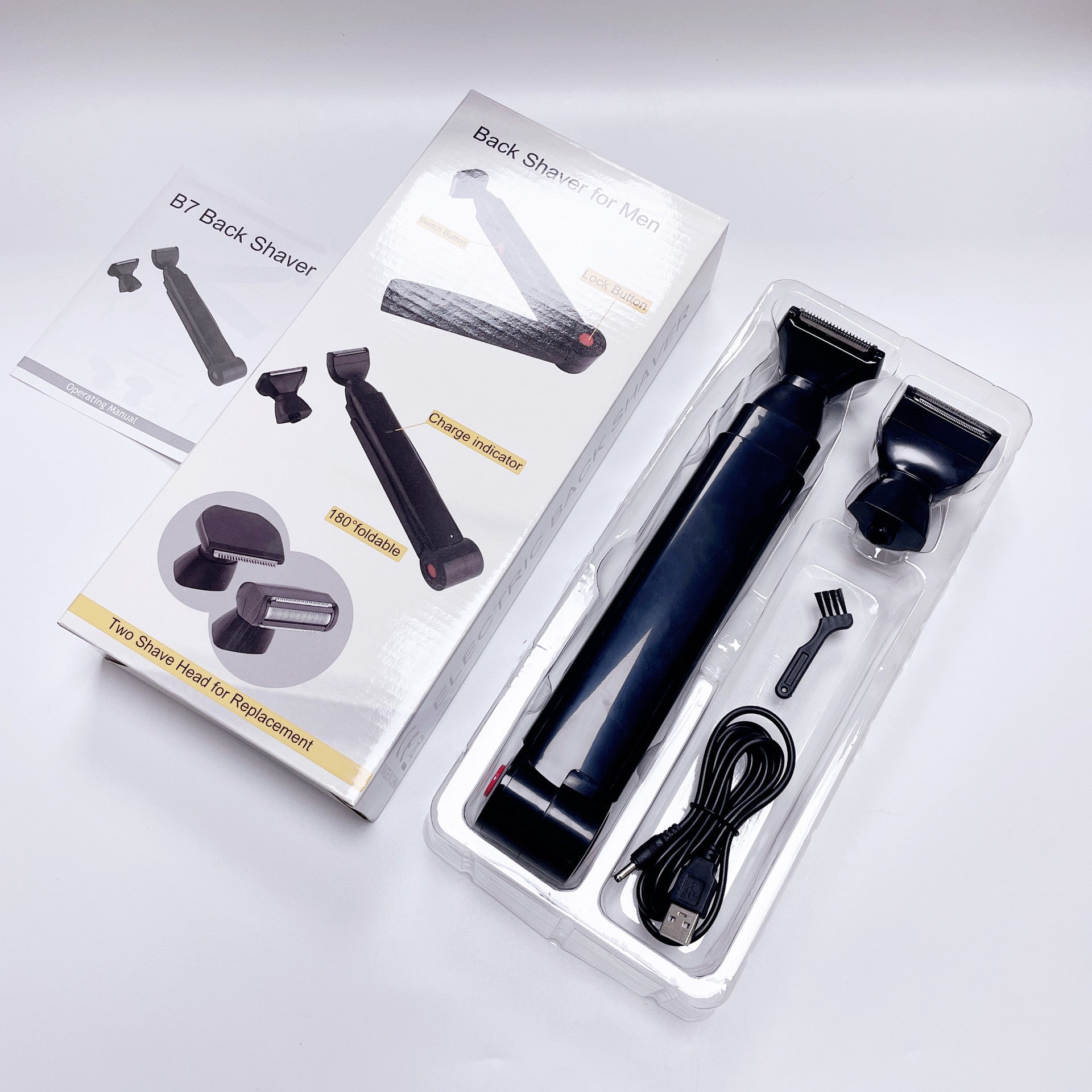 Black electric back shaver with multiple attachment heads, shown in a clear plastic blister pack alongside its retail box and instruction booklet on a light gray background.