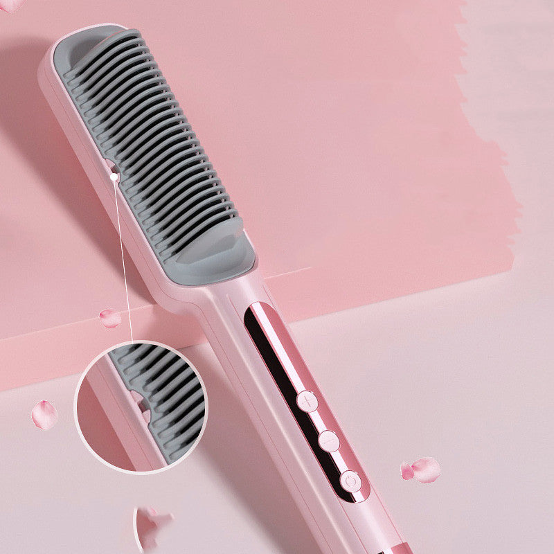 Hair straightening brush with pink handle and gray bristle head on a pink background
