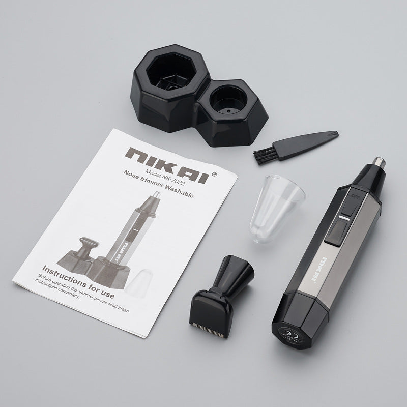 Nikai Model MK-C002 Nose Trimmer Washable kit on a light gray background, including the main silver and black trimmer, two black nozzle heads, a clear plastic cup, a small black brush, a black attachment, and an instruction booklet.