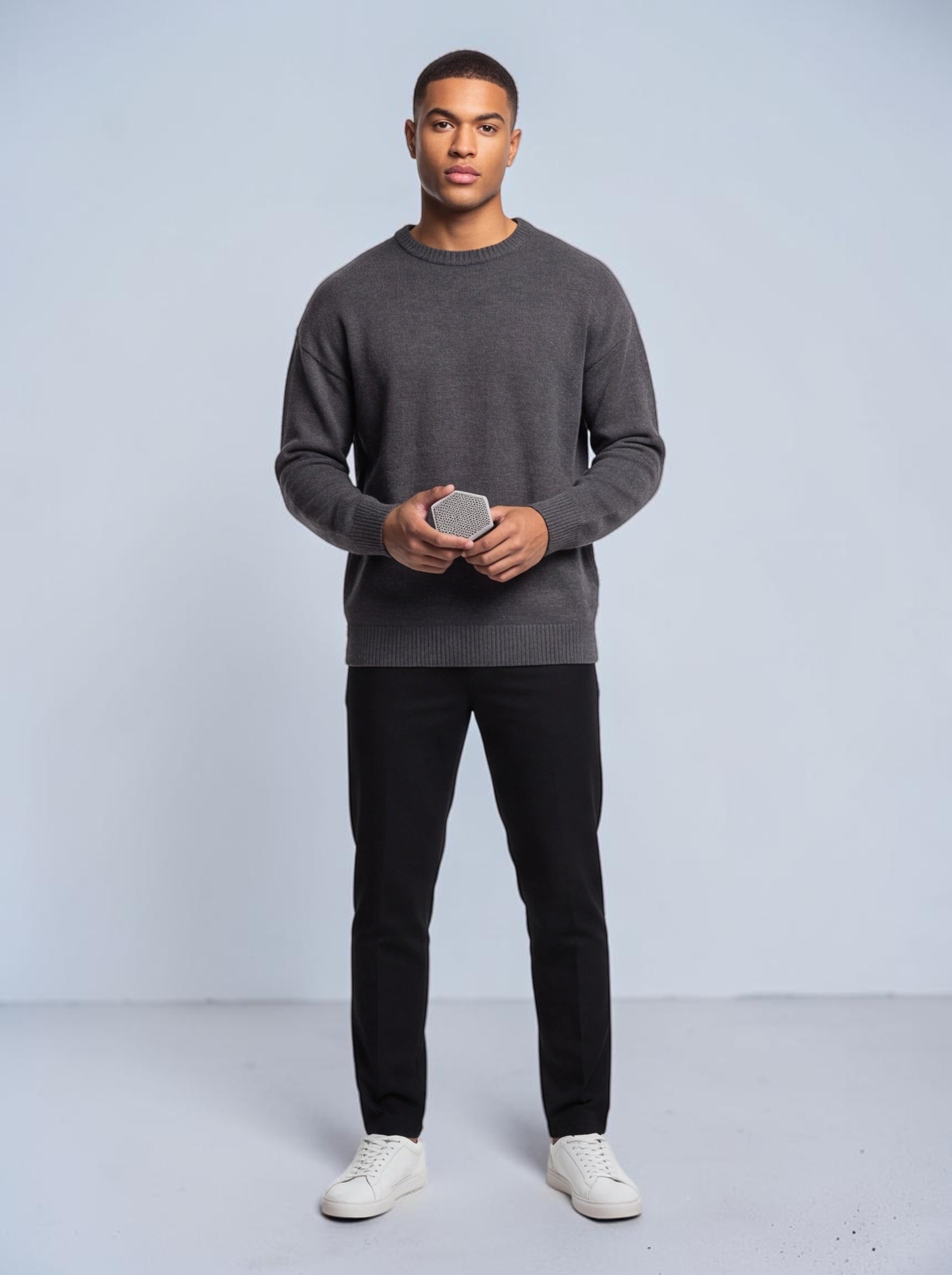 TheGromify silicone face and beard cleansing brush held by a man in a grey sweater for gentle exfoliation.