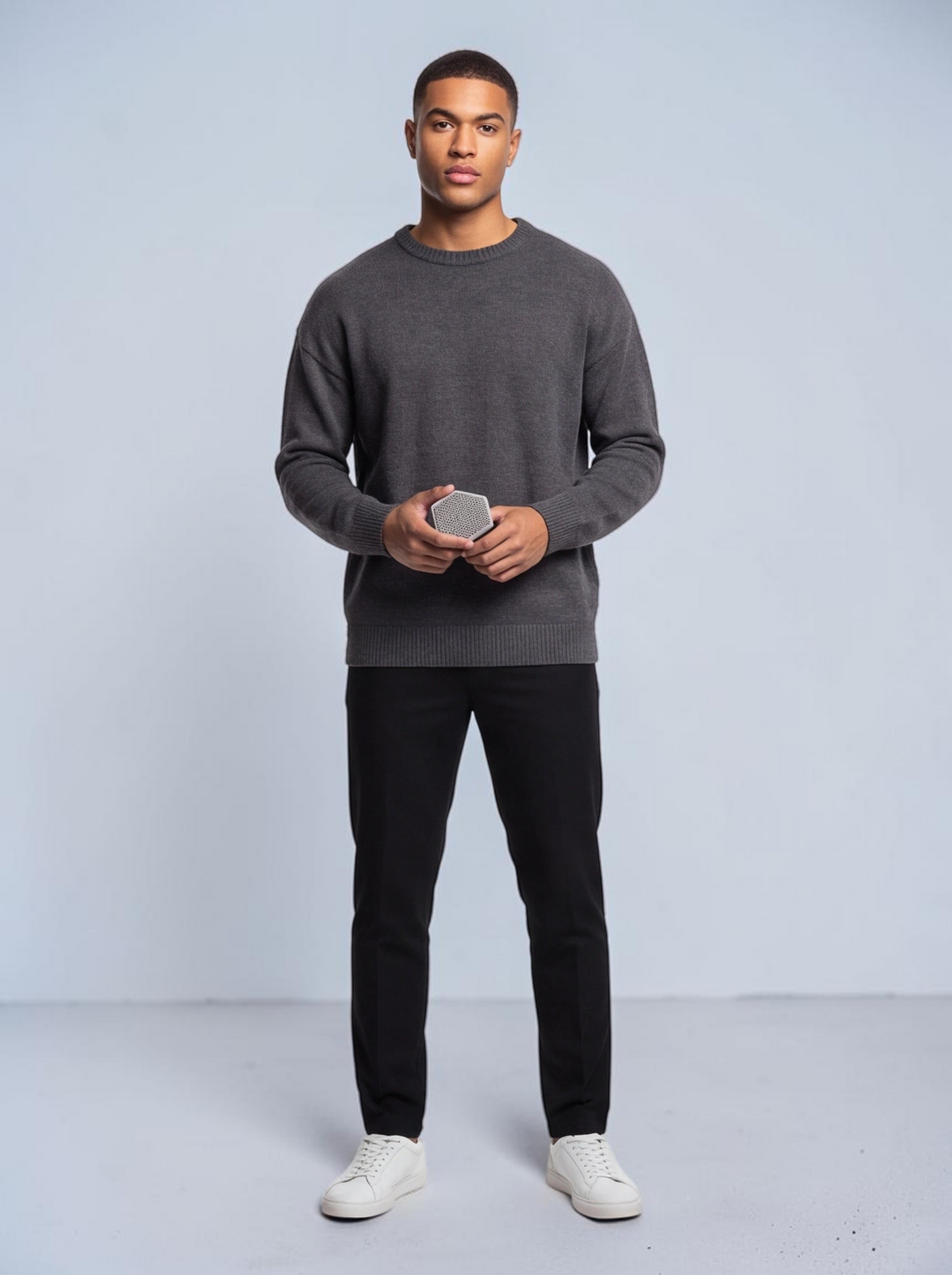 TheGromify silicone face and beard cleansing brush held by a man in a grey sweater for gentle exfoliation.