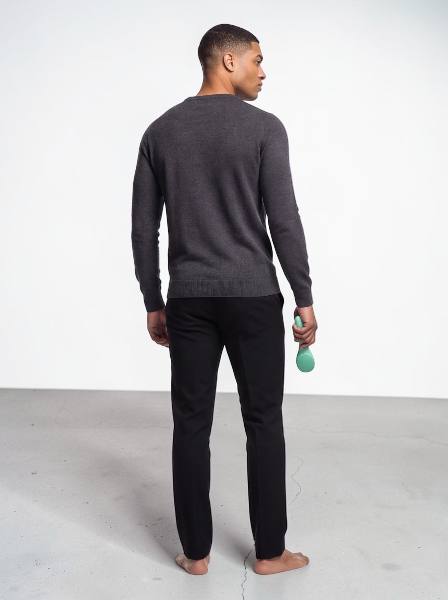 TheGromify ultrasonic silicone cleansing brush in green held by a man wearing a grey sweater and black trousers