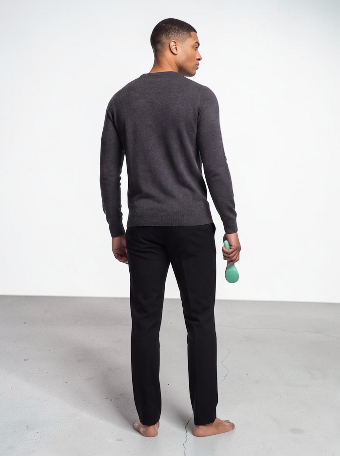 TheGromify ultrasonic silicone cleansing brush in green held by a man wearing a grey sweater and black trousers