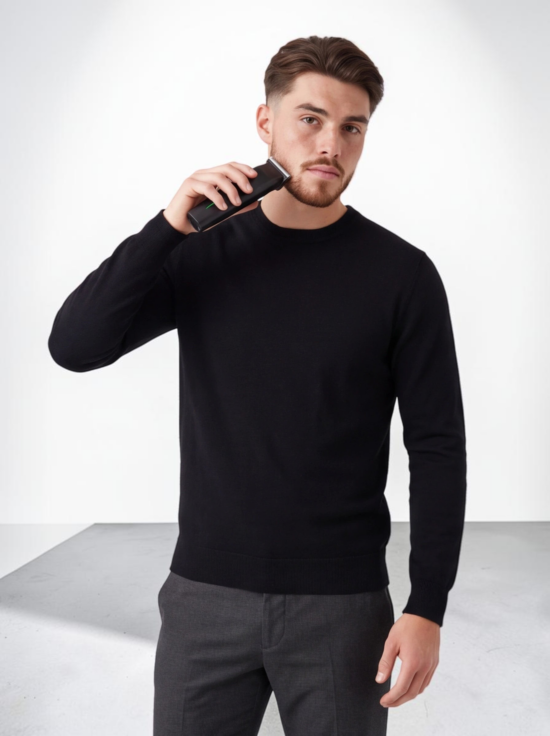 A man using a black TheGromify 3-in-1 cordless beard trimmer to groom his facial hair against a white background.