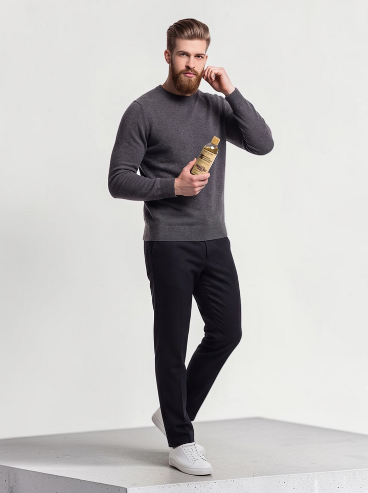 TheGromify Nourishing Beard Conditioner bottle held by a well-groomed man in a grey sweater against a white background