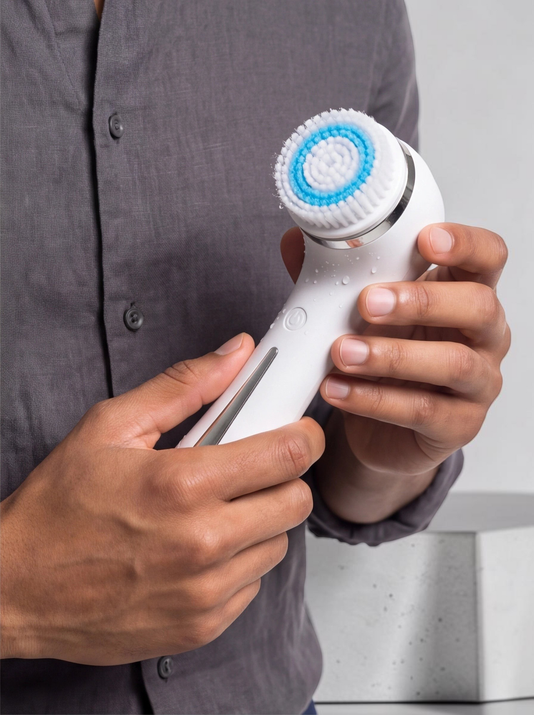 TheGromify electric facial cleansing brush with a white handle and blue rotating bristles held by a man