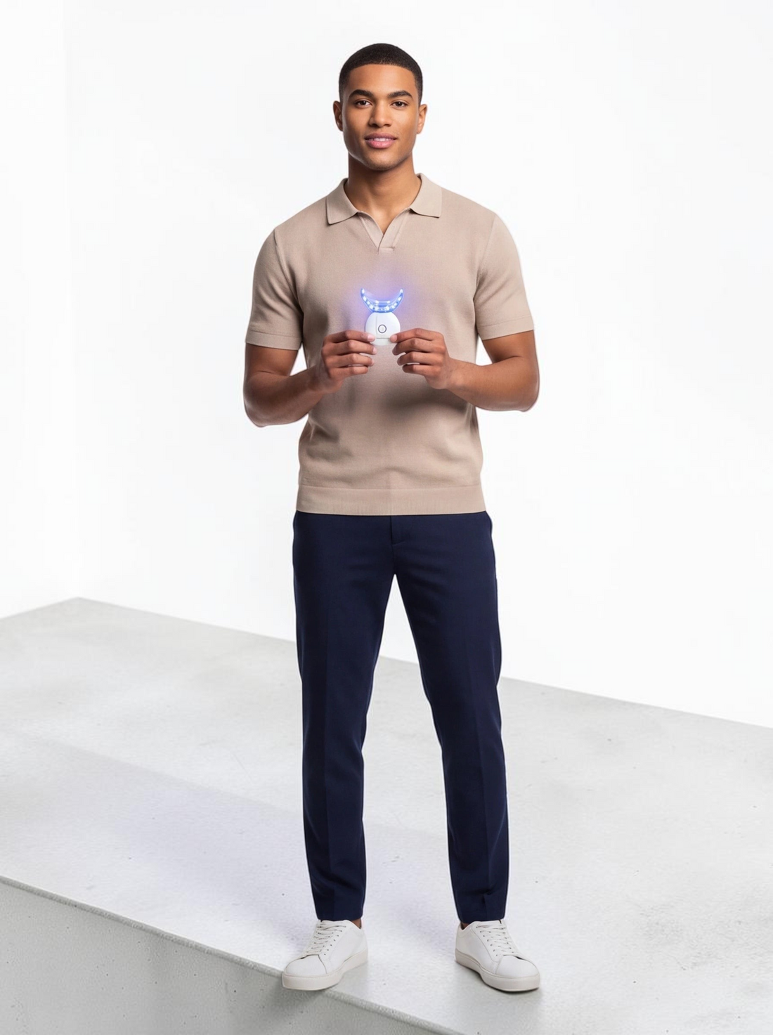 A man holding a TheGromify 32-LED teeth whitening tray that glows with blue light for at-home dental care.