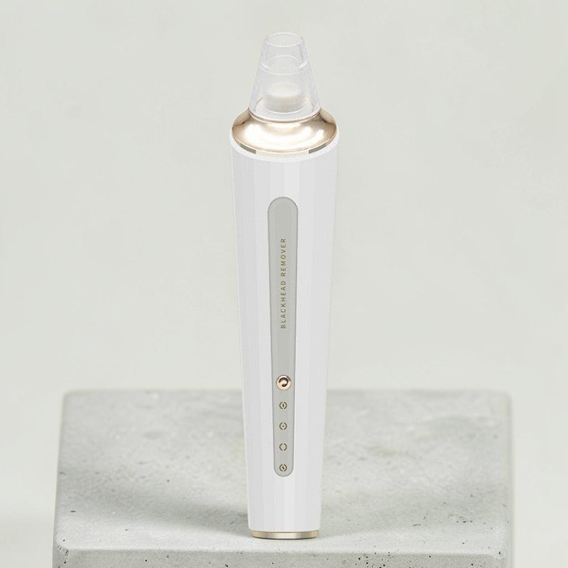 TheGromify electric pore vacuum and blackhead remover in white with gold accents, standing on a grey stone base.