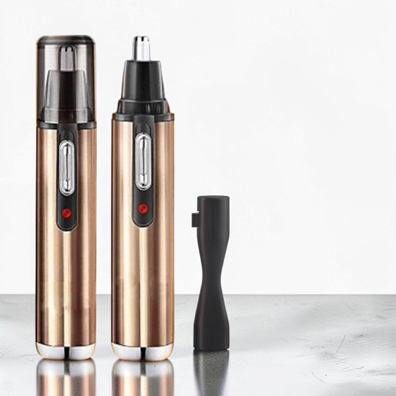 TheGromify electric nose and ear hair trimmer in gold with a protective cap and cleaning brush on a reflective surface.