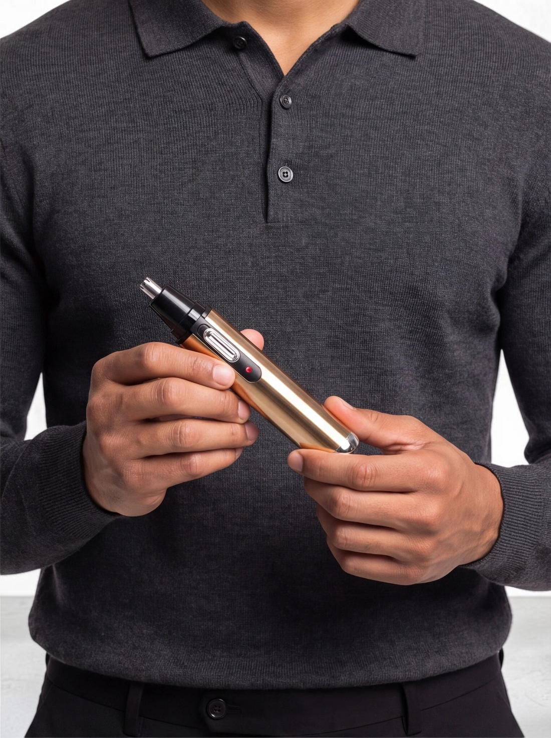 TheGromify gold electric nose and ear hair trimmer held by a man in a grey polo shirt for a polished grooming routine.