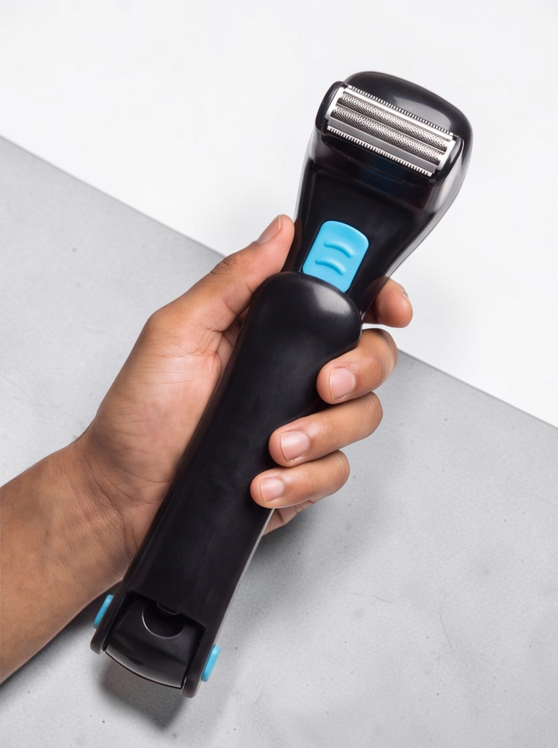 TheGromify long-handle back hair shaver with black ergonomic design and blue accents held in a hand