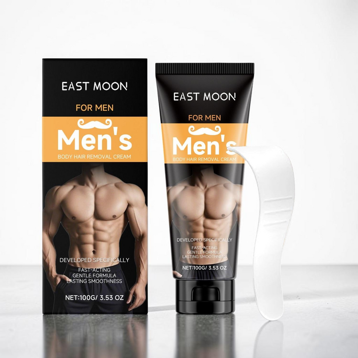 TheGromify East Moon men's body hair removal cream tube and box with a white applicator spatula on a grey surface.