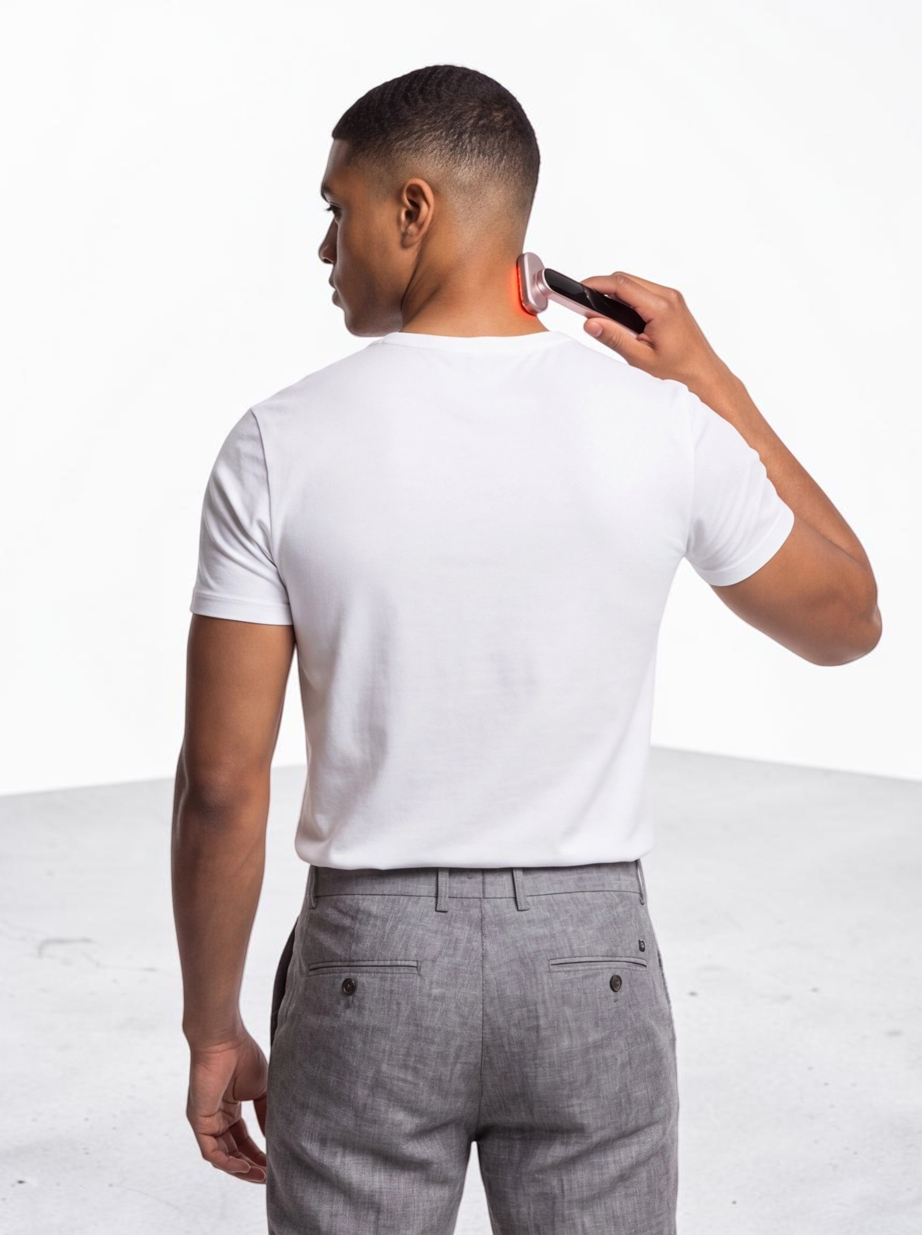 TheGromify 3-in-1 red light facial wand being used on the back of a man's neck against a white studio background.