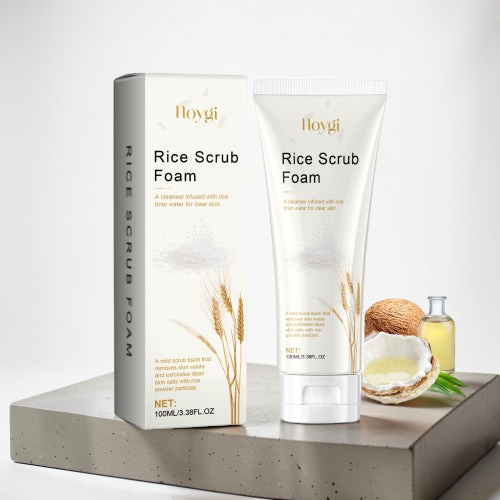 TheGromify Rice Scrub Foam cleanser in a white tube and box with rice grain illustrations on a grey stone platform.