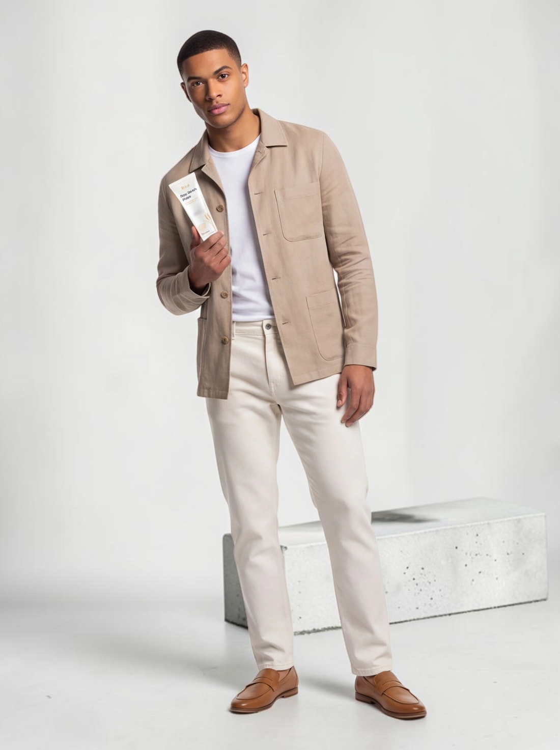 A man holding a TheGromify Rice Water Daily Face Cleanser tube while wearing a beige jacket and white trousers.
