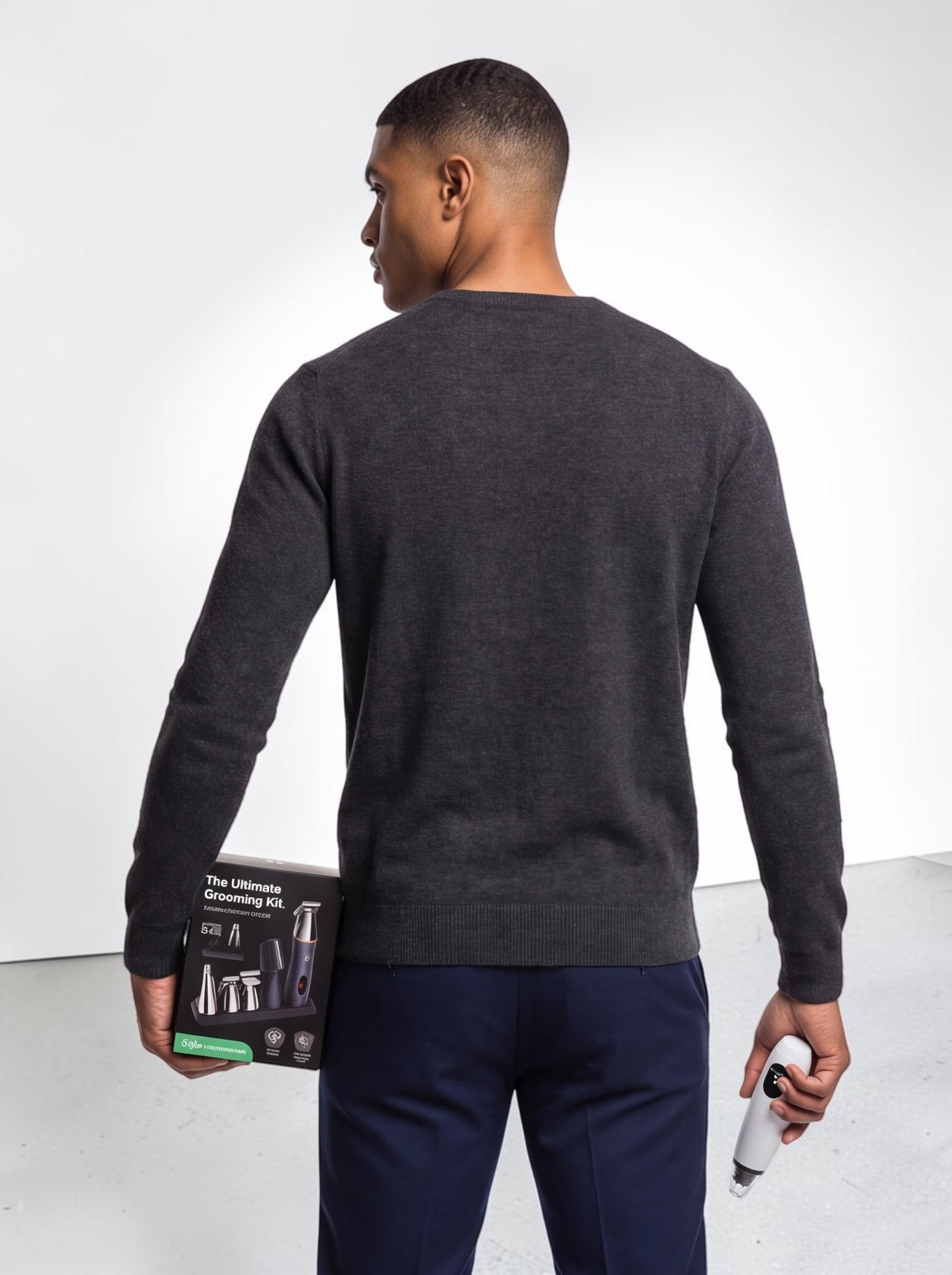 TheGromify Ultimate Grooming Kit box and electric trimmer held by a man wearing a dark grey sweater and navy trousers.