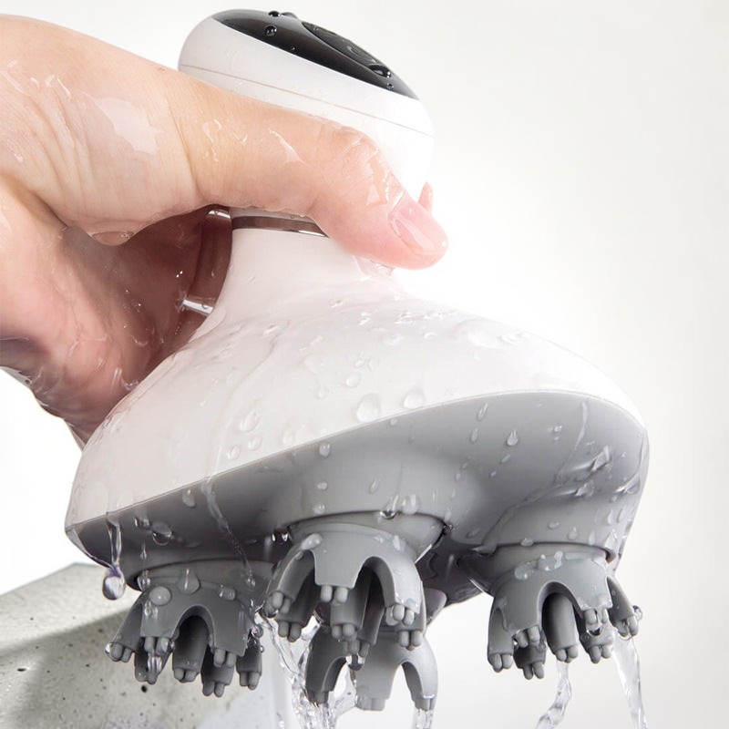 TheGromify wireless electric scalp massager with waterproof 3D kneading nodes being rinsed under running water