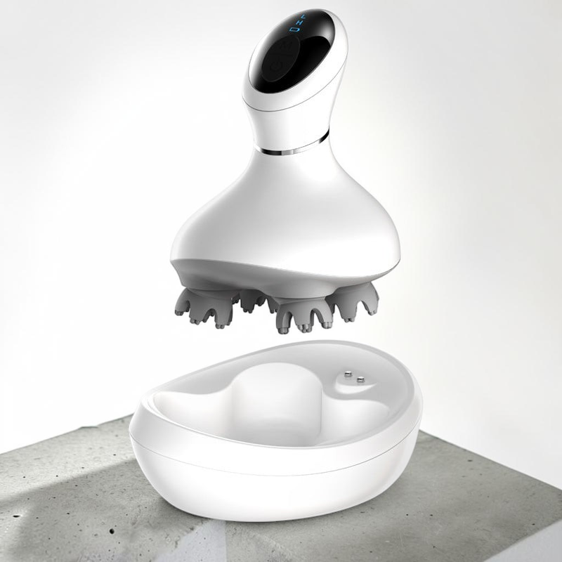 TheGromify wireless electric scalp massager with 3D kneading nodes and a white charging base on a concrete surface.