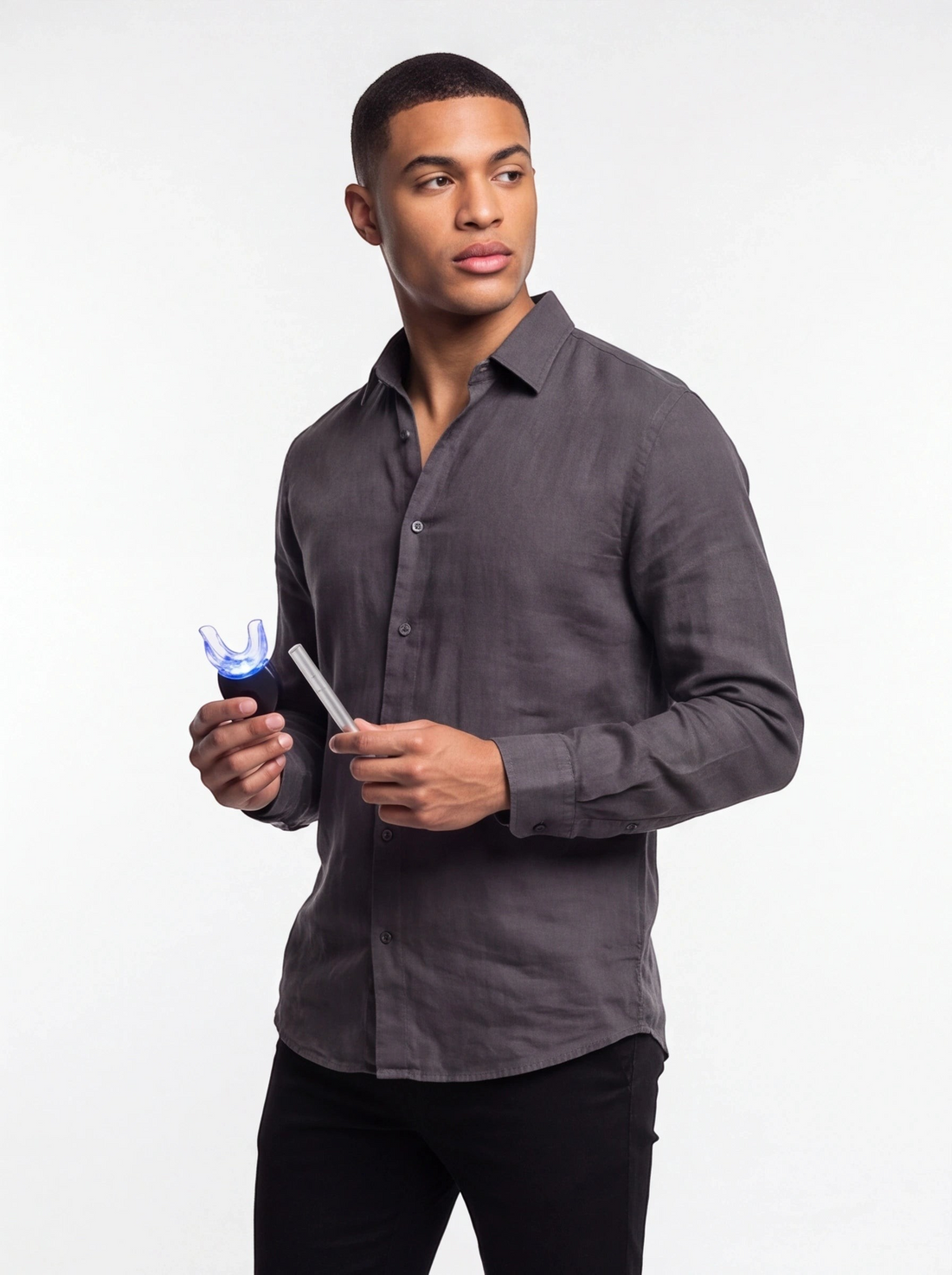 TheGromify wireless LED teeth whitening kit with blue light tray held by a man in a grey shirt against white background