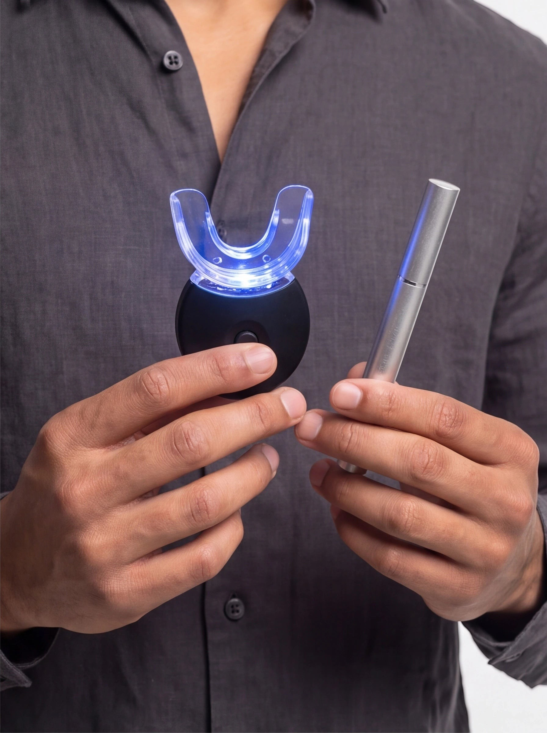 TheGromify wireless teeth whitening kit with blue LED U-shaped tray and whitening pen held by a person