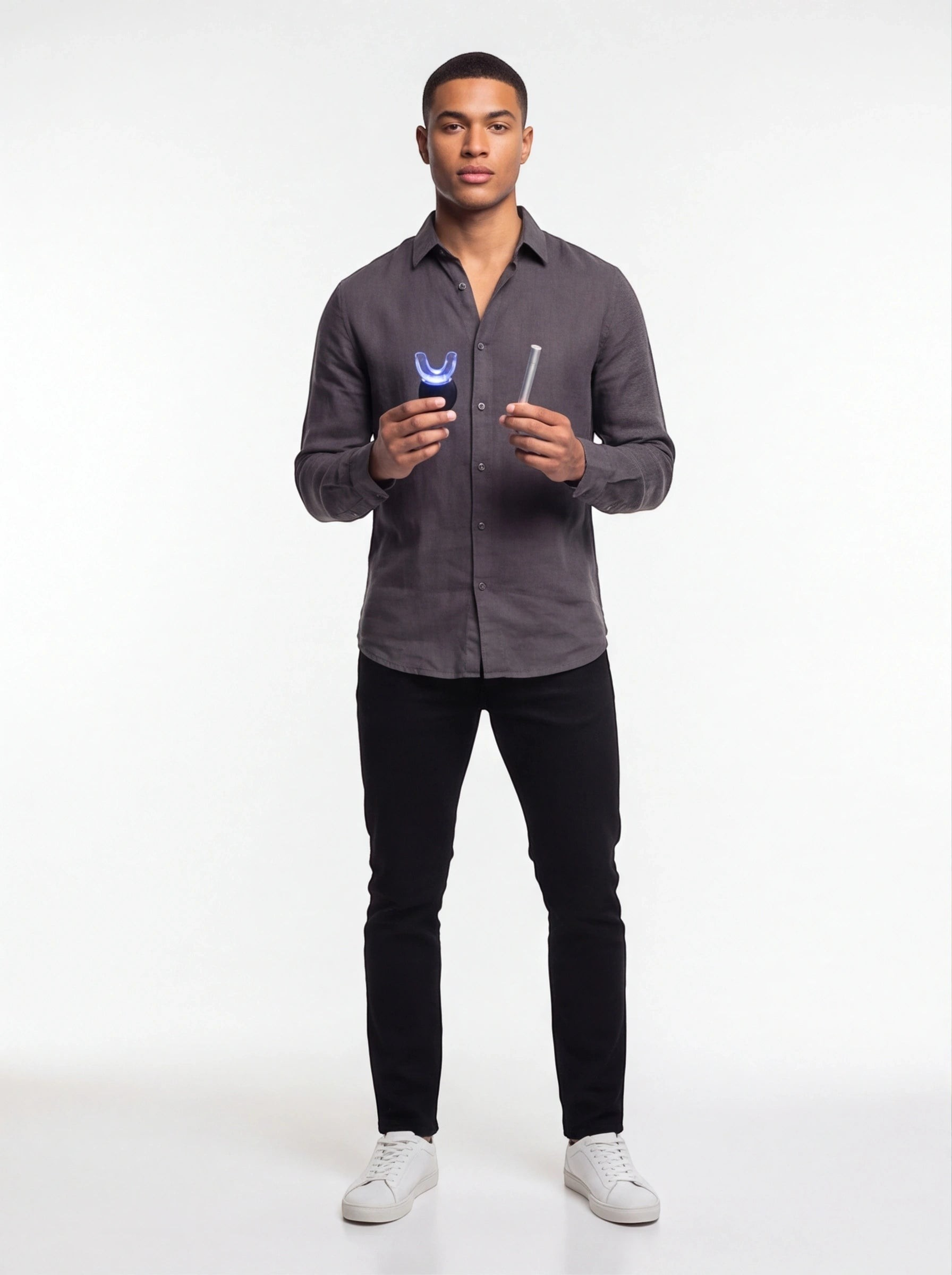 A man holding a TheGromify wireless LED teeth whitening kit with a blue light U-shaped tray and whitening gel pen.