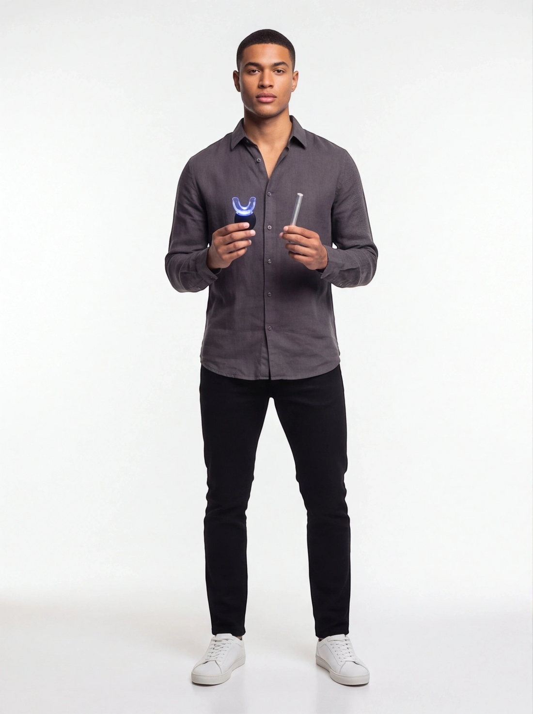 A man holding a TheGromify wireless LED teeth whitening kit with a blue light U-shaped tray and whitening gel pen.
