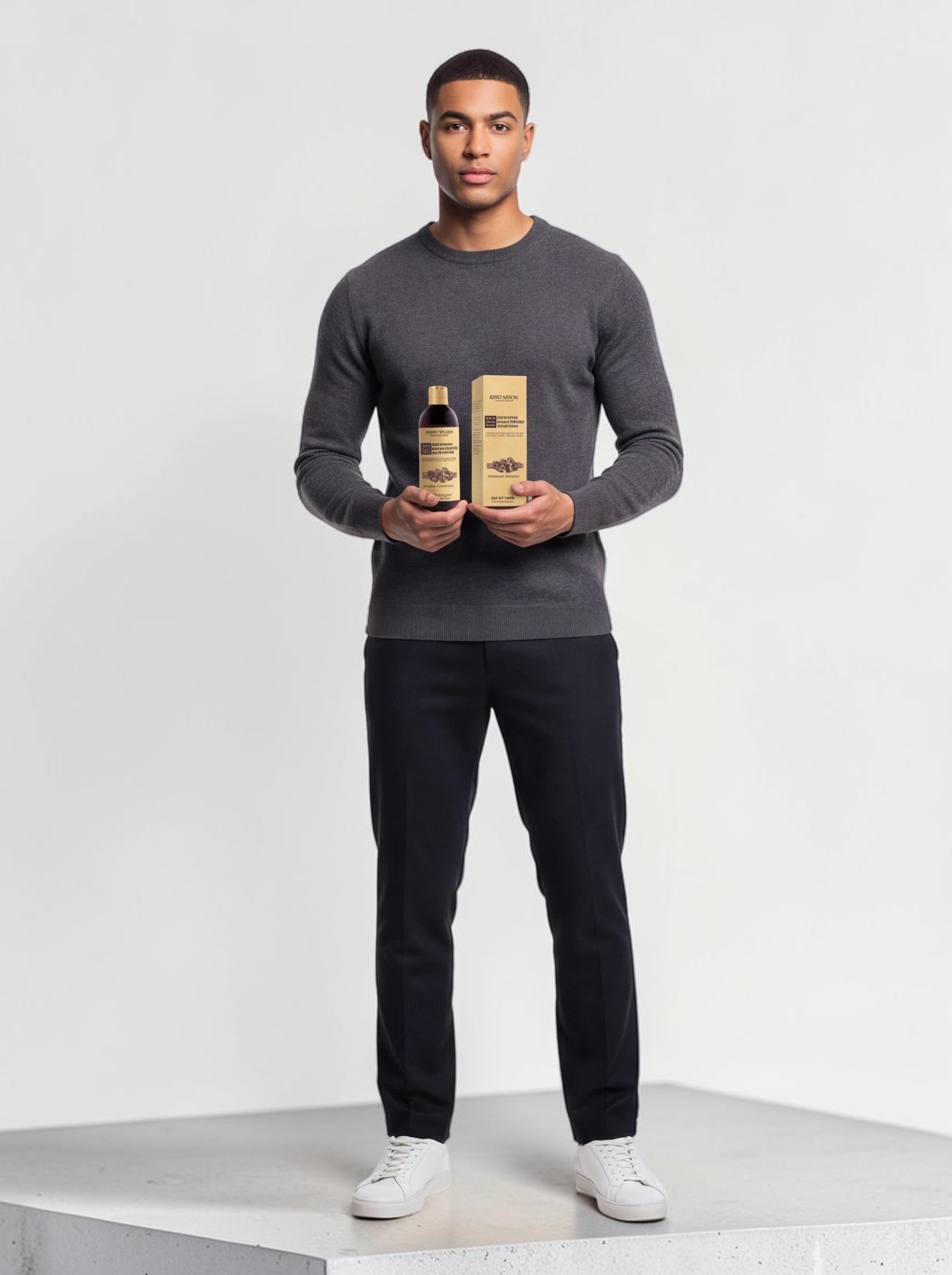 A man in a grey sweater holding a bottle and box of TheGromify Nourishing Beard Conditioner against a white background