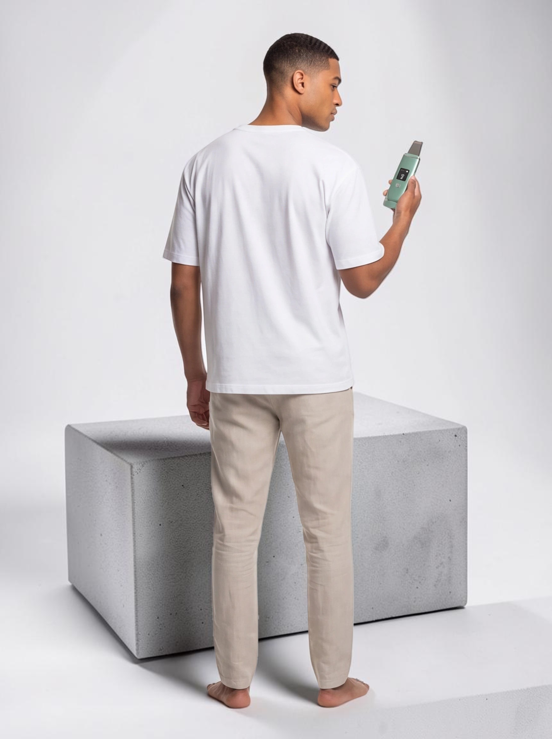 TheGromify ultrasonic skin spatula held by a man in a white t-shirt, showing the LED display and metal blade.