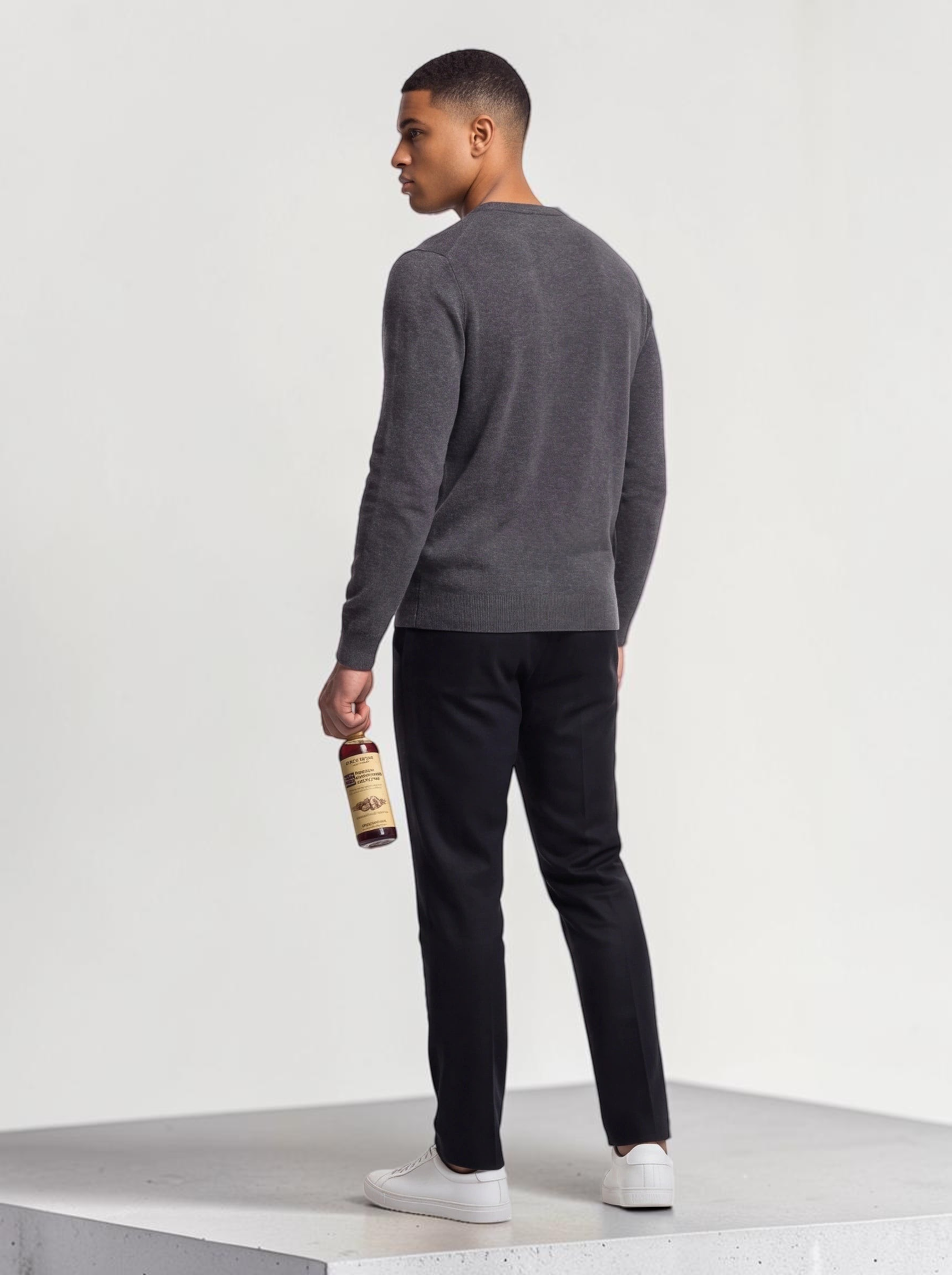 TheGromify Nourishing Beard Conditioner bottle held by a man wearing a grey sweater and black trousers